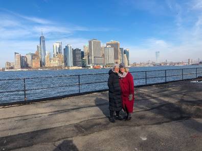 A person and person standing on a dock with a city in the background  Description automatically generated with medium confidence